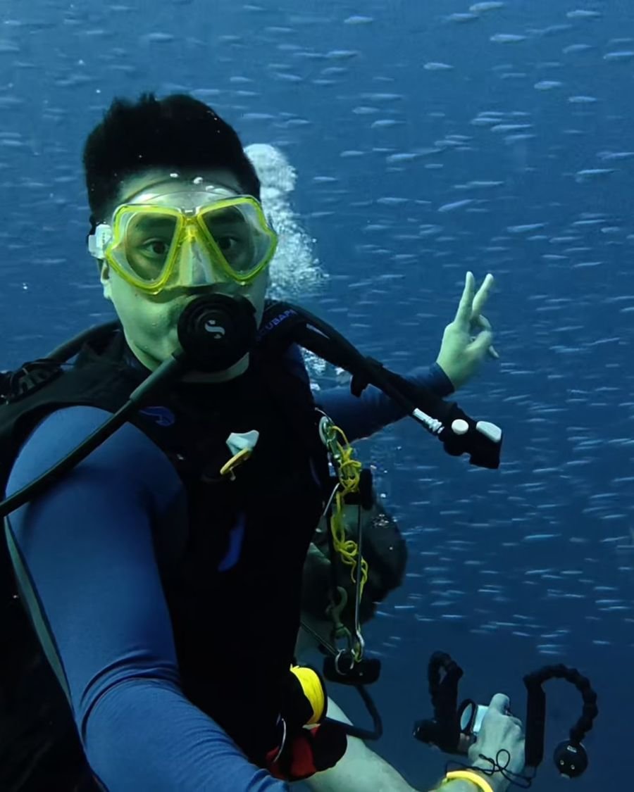 Vinh in a school of fish with a shark behind